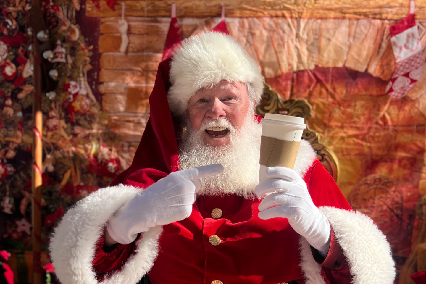 Santa holding a to-go style coffee cup.