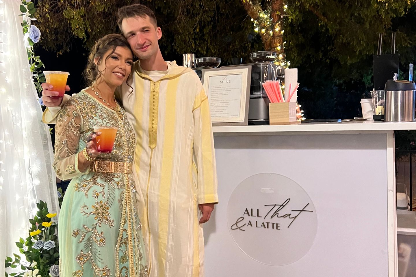 Man and women in elegant wedding clothing in front of mobile coffee bar.